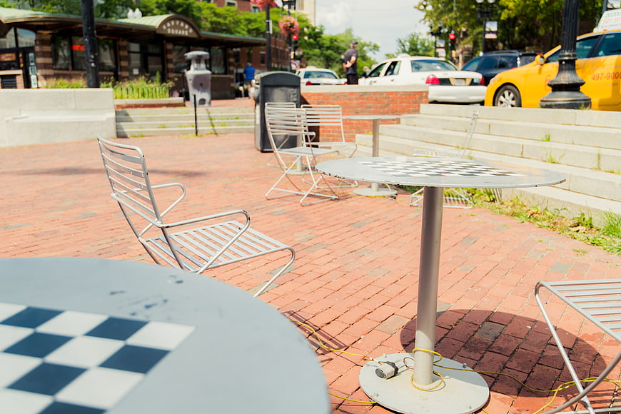 Empty outdoor cafe tables and chairs on brick plaza