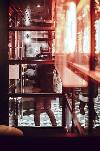 Man entering restaurant through glass door at night