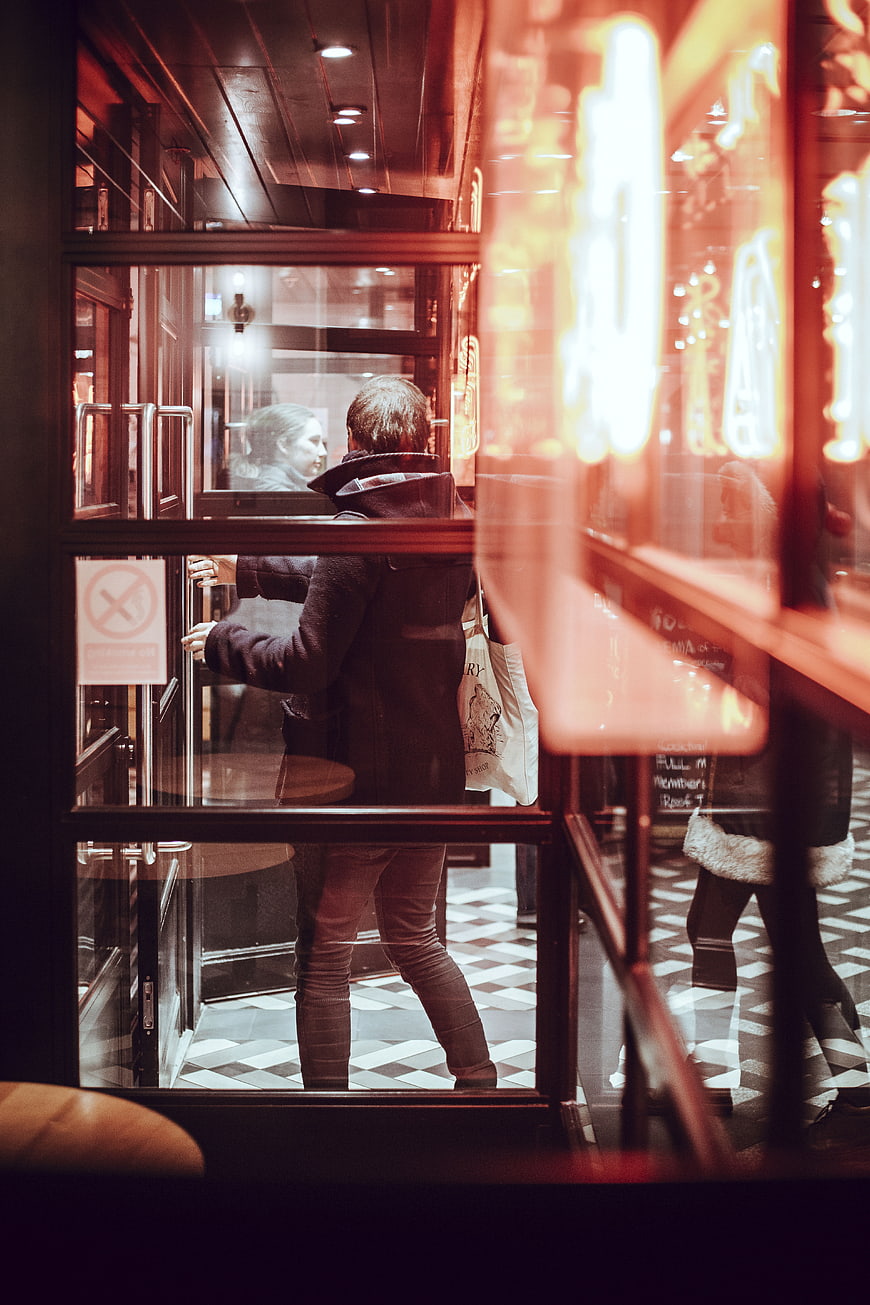 Man entering restaurant through glass door at night