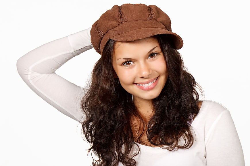 Smiling young woman with long dark hair wearing a brown cap