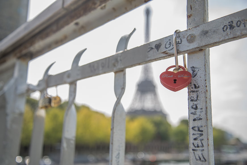 Red heart padlock on Paris bridge railing with Eiffel Tower background