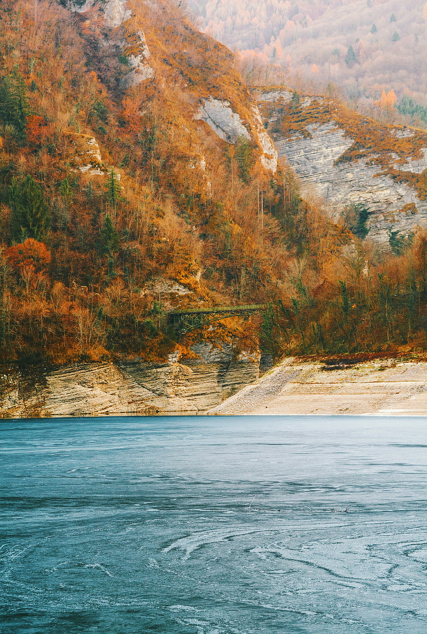 Frozen Lake with Autumn Mountain Cliff and Bridge