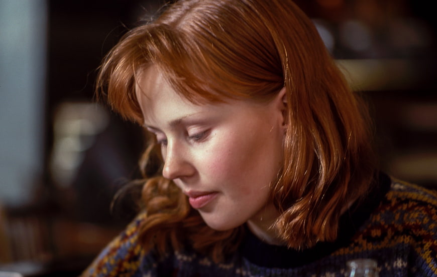 Close-up portrait of a contemplative red-haired woman looking down