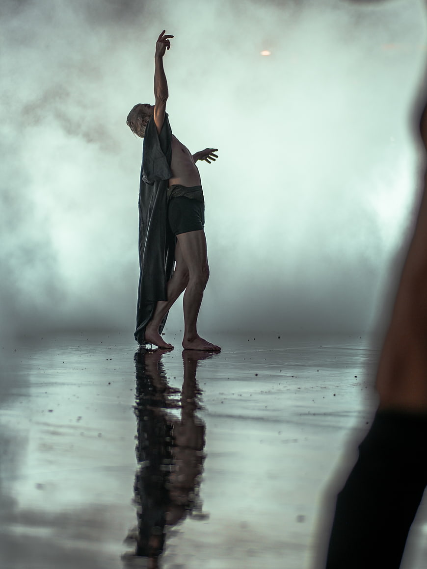 Male dancer in dramatic pose with fog and reflection