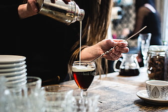 Barista pouring cream into Irish coffee glass