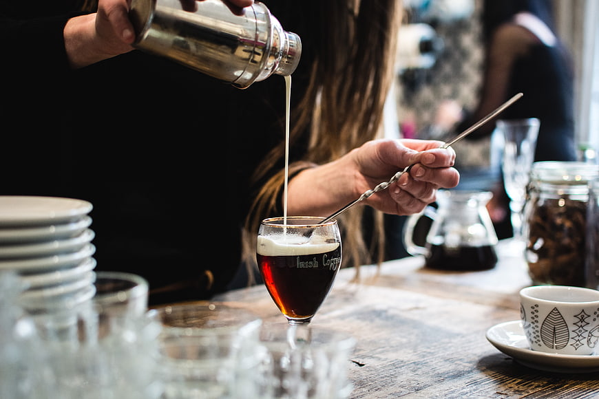 Barista pouring cream into Irish coffee glass
