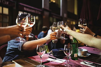 Friends toasting with white wine glasses at a restaurant