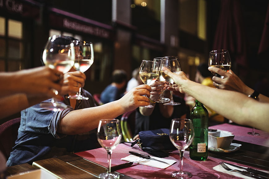 Friends toasting with white wine glasses at a restaurant