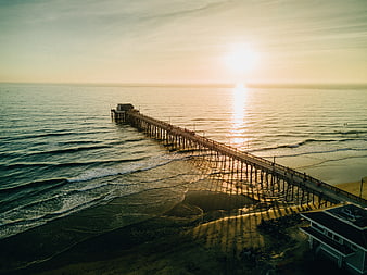 Aerial view of a long pier at sunset over the ocean