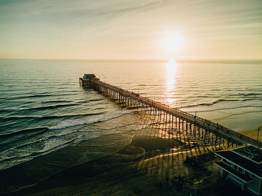 Aerial view of a long pier at sunset over the ocean