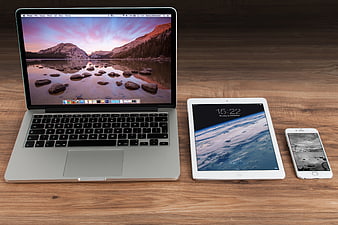 MacBook, iPad, and iPhone on wooden desk workspace
