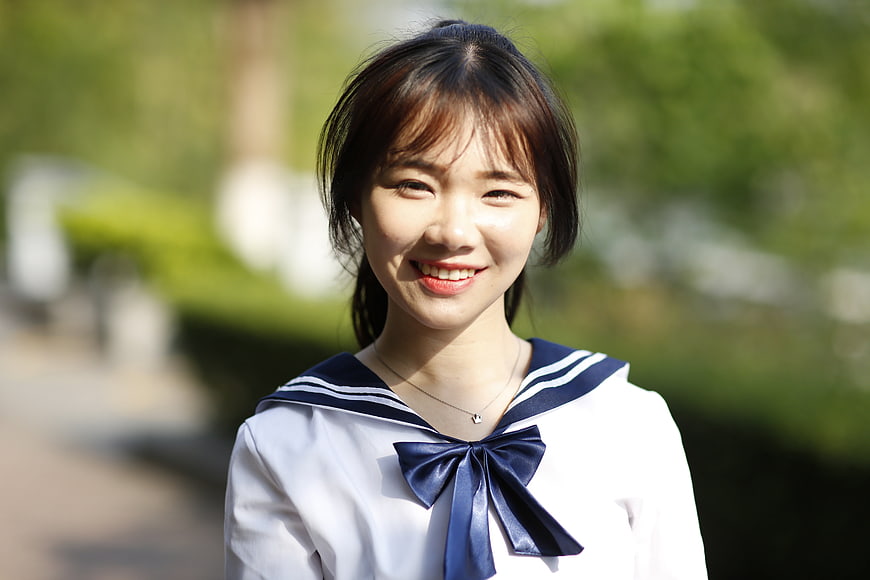 Smiling young Asian woman in sailor school uniform outdoors