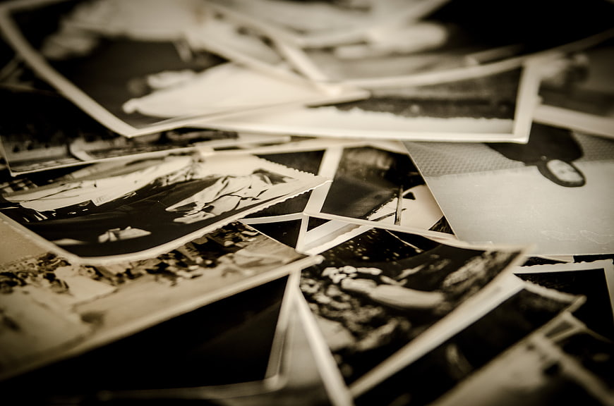 Scattered vintage black and white photographs on a dark surface