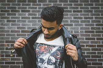 Young man in leather jacket against brick wall
