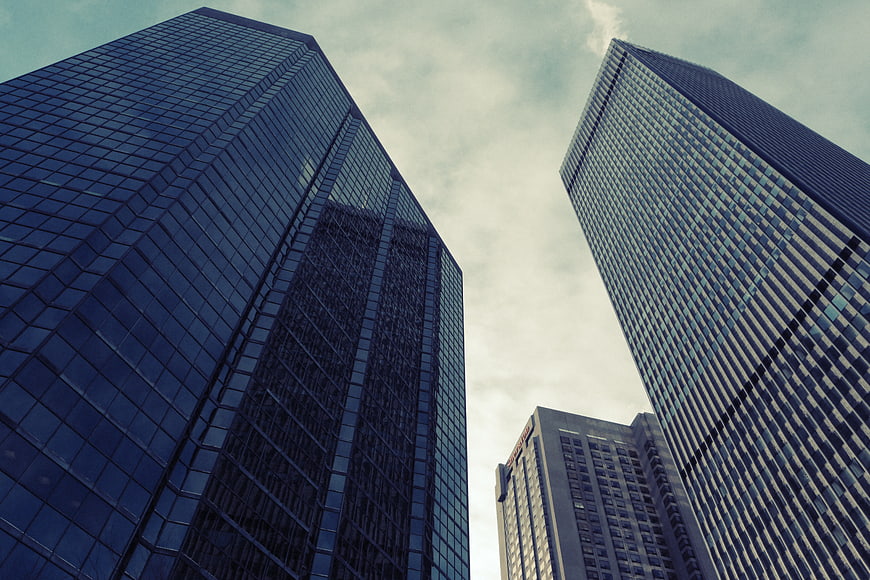 Low angle view of modern glass skyscrapers against cloudy sky