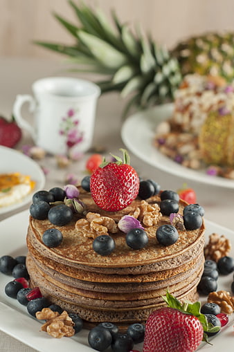 Stack of pancakes with strawberries, blueberries, and walnuts