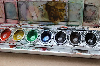 Close-up of used watercolor paint palette with mixed colors