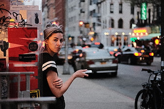 Woman waiting on busy city street holding smartphone