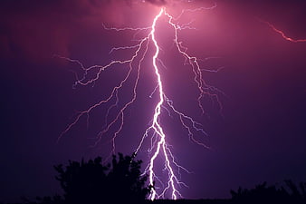 Dramatic purple lightning bolt striking through stormy night sky
