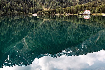 Serene Alpine Lake with Forest Reflection and Mountain Lodge