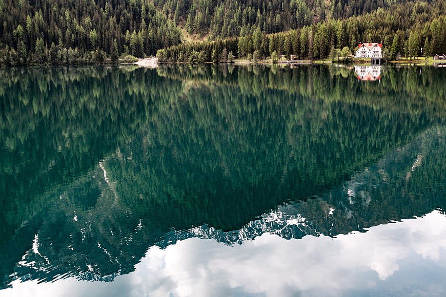 Serene Alpine Lake with Forest Reflection and Mountain Lodge