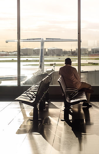 Man Sitting Alone in Airport Terminal Waiting for Flight