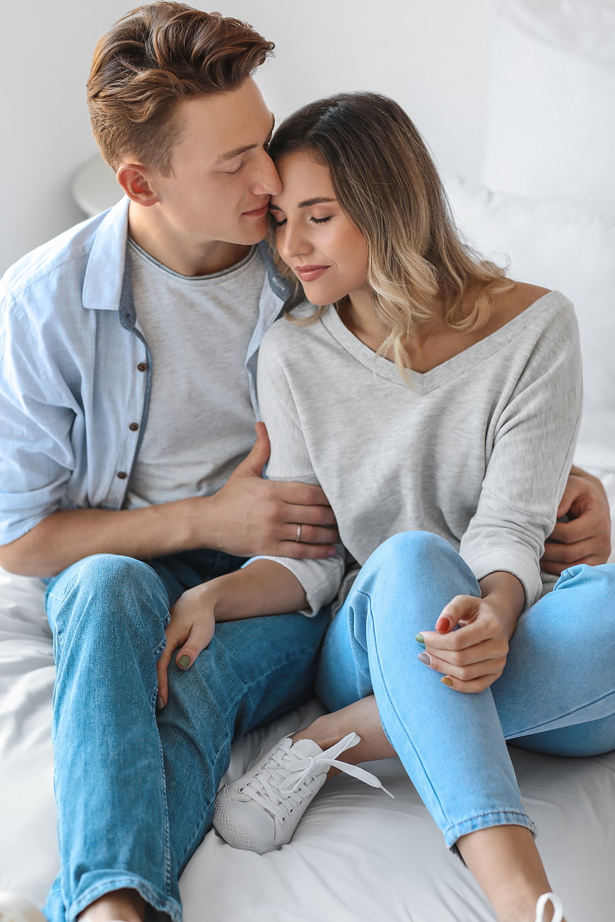 Affectionate young couple embracing on a white bed