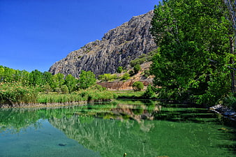 Serene River Landscape with Mountain Reflection and Lush Greenery