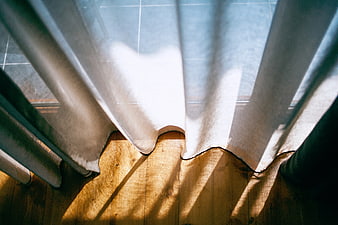 Sunlight streaming through sheer curtains onto wooden floor