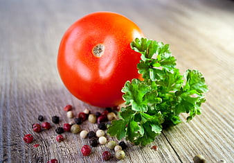 Fresh red tomato with parsley and peppercorns on wood