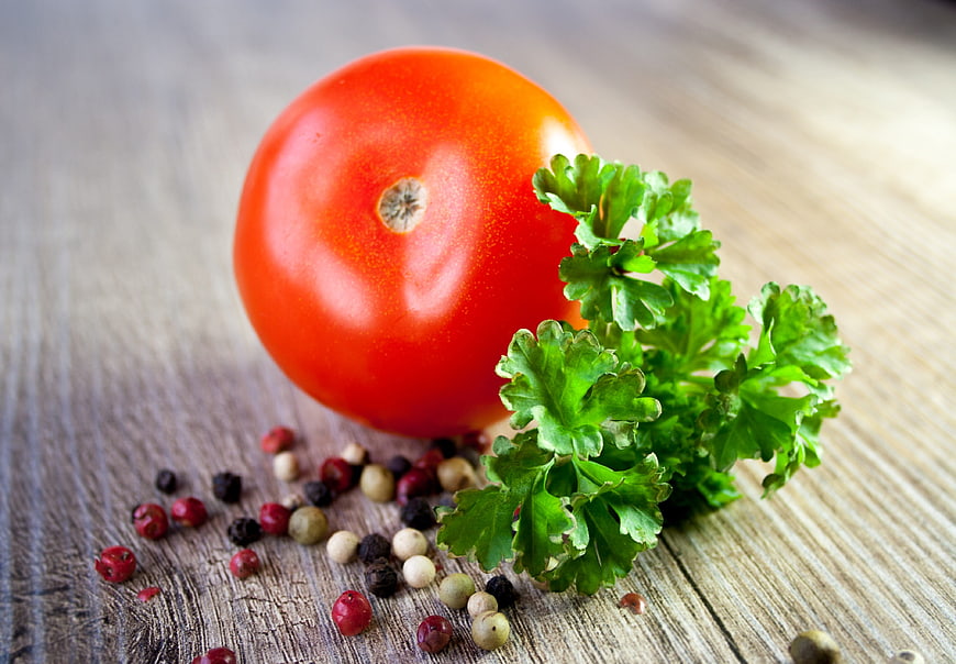 Fresh red tomato with parsley and peppercorns on wood