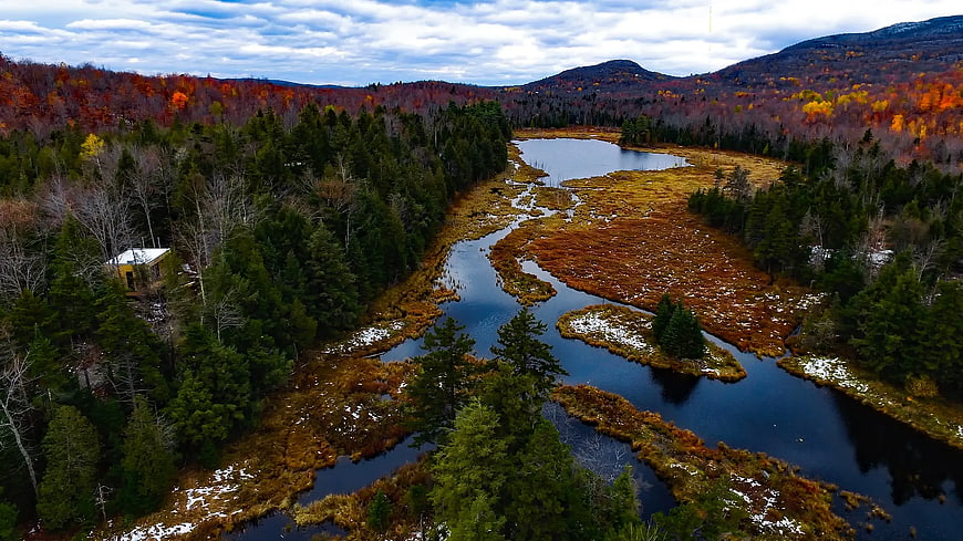 Aerial View of Cabin Near River and Autumn Forest