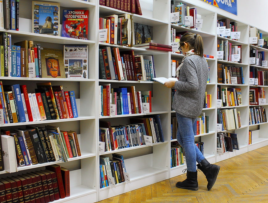 Woman browsing books in a library aisle