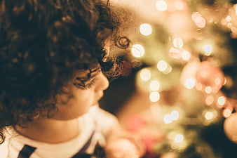 Toddler with curly hair looking at Christmas tree lights