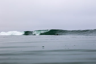 Surfer riding a wave in the ocean on an overcast day