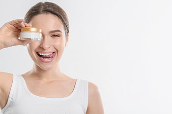 Happy woman holding skincare cream jar with copy space