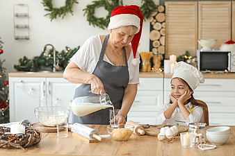 Grandmother and granddaughter baking Christmas cookies in festive kitchen
