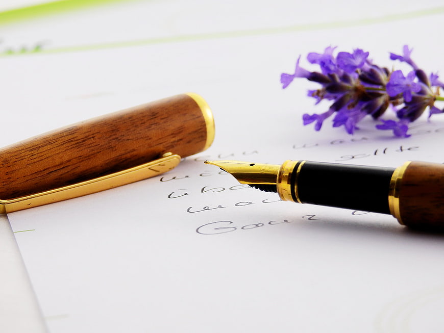 Wooden fountain pen with lavender on handwritten paper