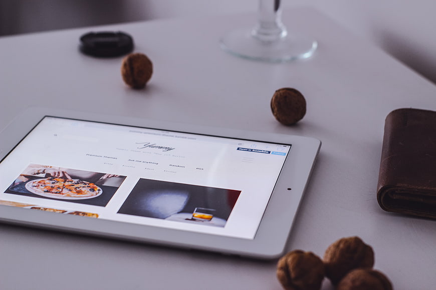 Tablet displaying website on white desk with walnuts