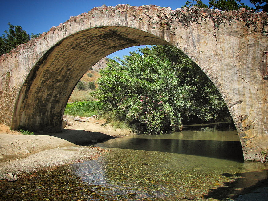 Ancient stone arch bridge over clear river stream