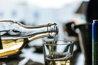 White wine being poured from a glass bottle into a clear glass