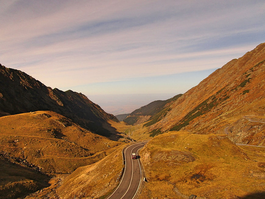 Winding Mountain Road with Red Car in Autumn Landscape