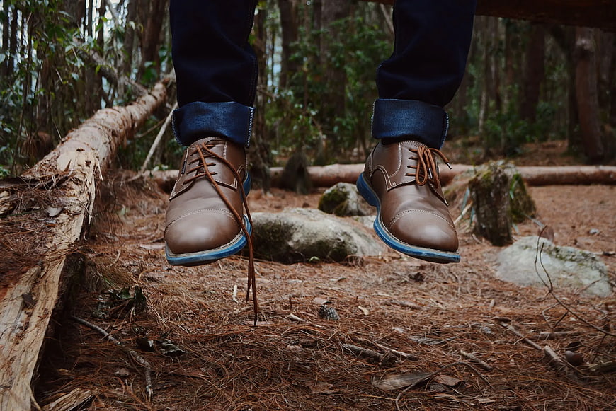 Man Wearing Brown Leather Shoes and Jeans in Forest