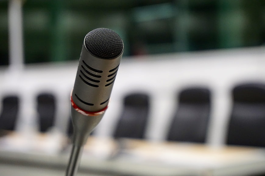 Close-up of silver conference microphone with blurred meeting room background
