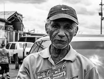 Portrait of elderly man in cap holding product packaging