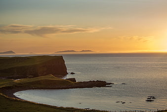 Golden sunset over rugged coastal cliffs and calm ocean