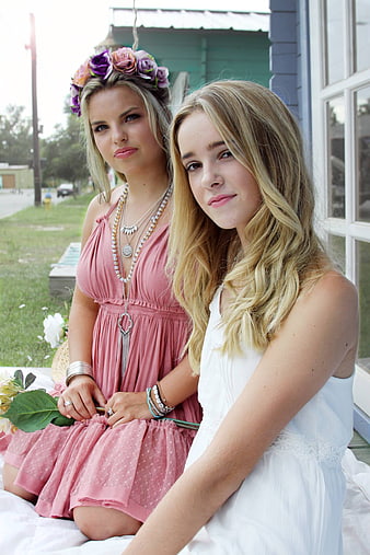 Two young women in summer dresses sitting on a porch