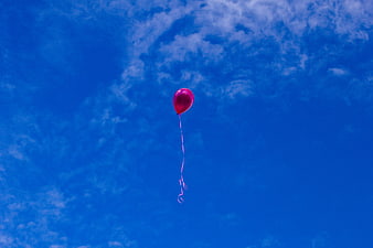 Pink Balloon Floating in Blue Sky with Clouds