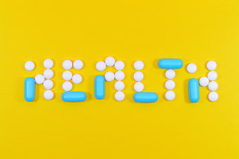 Health word spelled with white and blue pills on yellow background