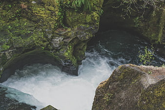 Mossy Cliff Overlooking Turbulent River Waterfall